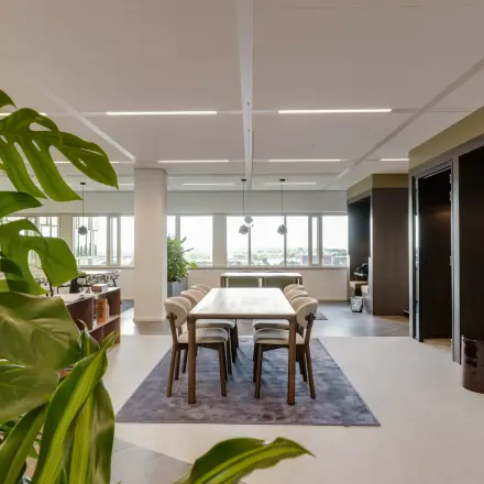 Bright and open office space with a large table and chairs, surrounded by greenery, available for rent at Herikerbergweg 290, Amsterdam South East.