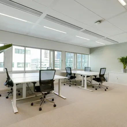 Bright office space for rent at Herikerbergweg 290, Amsterdam South East, featuring modern desks and chairs, with views of surrounding buildings.