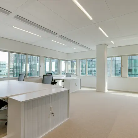 Bright office space rental at Herikerbergweg 290, Amsterdam South East, featuring modern desks and chairs in a light-filled room.