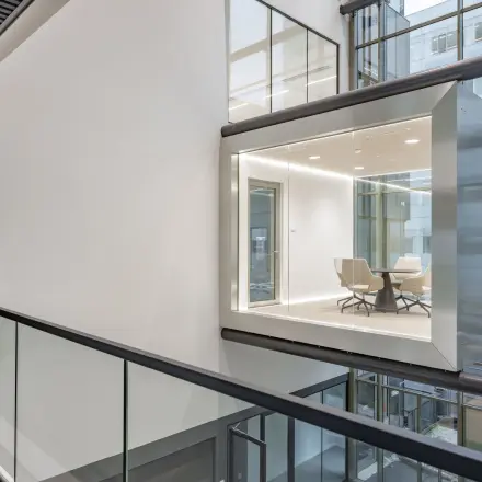 Modern office to rent at Herikerbergweg 290, Amsterdam South East, featuring sleek, glass-enclosed workspaces overlooking the building's atrium, ideal for office space rental.