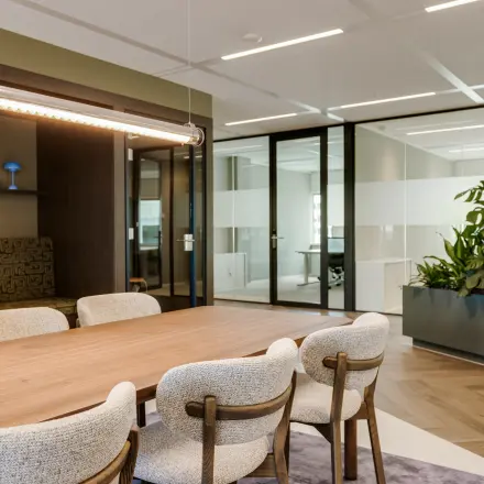 Furnished office space at Herikerbergweg 290 in Amsterdam South East with a large table, chairs, and indoor plants, ideal for those looking to rent office space.