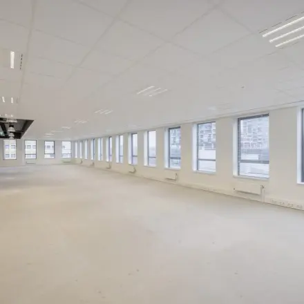 An unfurnished office space for rent at Hogehilweg 24, Amsterdam South East, featuring large windows and ample lighting, ideal for customizing to your business needs.