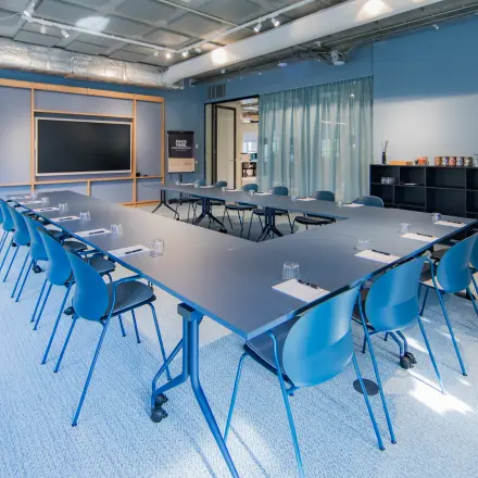 Bright conference room at Hullenbergweg 109-135, Amsterdam South East, featuring a large rectangular table with chairs and a presentation screen. Ideal for office space rental.