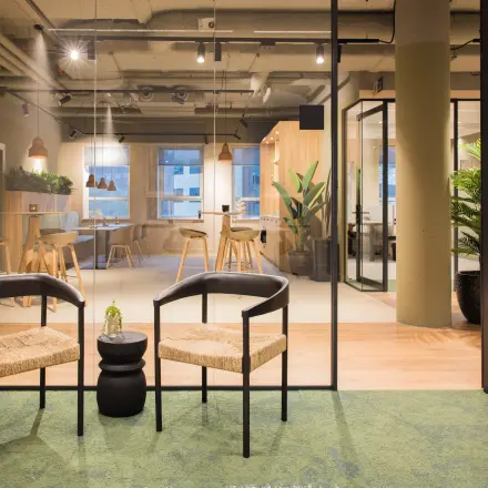 Modern office space in Amsterdam South East at Hullenbergweg 109-135, featuring a stylish interior with seating, glass partitions, and greenery, perfect for an office to rent.