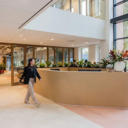 Modern office reception area at Hullenbergweg 109-135 in Amsterdam South East with a sleek reception desk and vibrant indoor plants. Ideal for those looking to rent office space in a stylish environment.