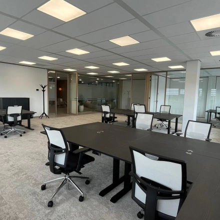 Interior view shows a furnished workspace at Laarderhoogtweg 7-19 in Amsterdam South East, ideal for office space rental with multiple desks and chairs under bright lighting.