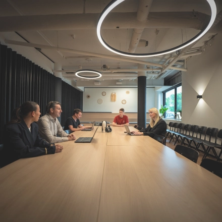 Individuals engaged in a meeting at a long table in a modern office space located at Luttenbergweg 8, Amsterdam South East, ideal for office space rental.