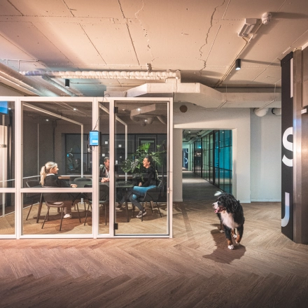 Modern office interior at Luttenbergweg 8, Amsterdam South East, featuring a meeting room with people engaged in discussion, highlighting a vibrant option for office space rental.