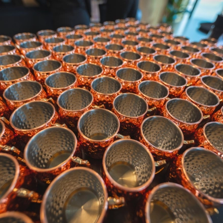 Copper cups are neatly arranged in rows on a table at Luttenbergweg 8, Amsterdam South East, showcasing a unique feature of the office space rental.