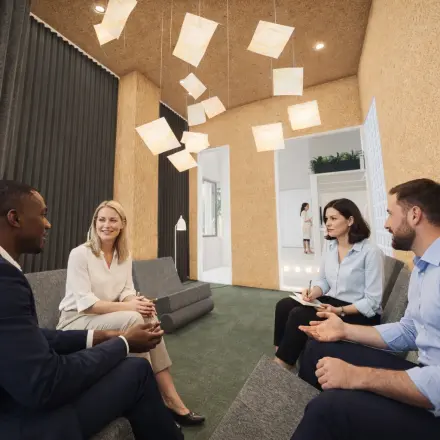 People engaged in a business discussion in a contemporary office with modern lighting at Luttenbergweg 8, Amsterdam South East. Ideal office space rental for professionals.