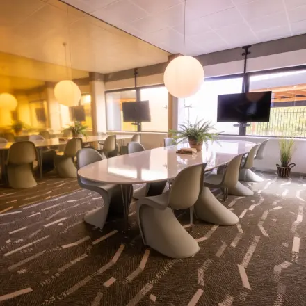 Bright conference room with modern chairs and large table, featuring natural light and a TV screen. Perfect for office space rental at Luttenbergweg 8, Amsterdam South East.