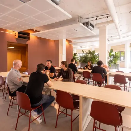 Modern furnished office space at Luttenbergweg 8, Amsterdam South East, featuring people engaged in collaborative work at tables, ideal for office space rental.