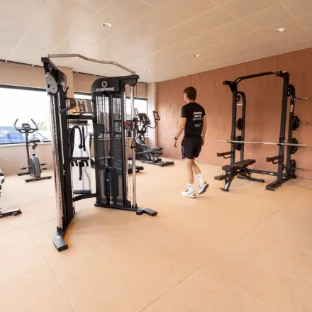 Office gym at Luttenbergweg 8 with fitness equipment and a person working out, ideal for office space rental in Amsterdam South East.