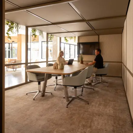 Interior view of a furnished office space at Luttenbergweg 8 in Amsterdam South East, featuring two people engaged in a meeting. This office space rental offers a comfortable environment for business activities.
