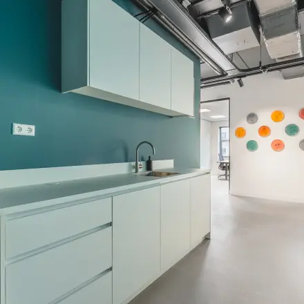 Modern office kitchen area at Paasheuvelweg 20, Amsterdam South East, featuring sleek cabinets and a spacious layout for convenient office space rental.