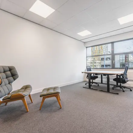 Bright office space with modern furniture, featuring a desk and chairs, located at Paasheuvelweg 20 in Amsterdam South East, ideal for office space rental.