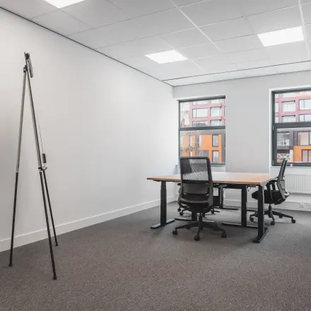 Office space for rent at Paasheuvelweg 20 in Amsterdam South East, featuring two desks and chairs with windows offering natural light.