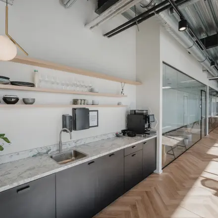 Modern office interior at Bos en Lommerplein 280 with sleek cabinetry, a marble countertop, and glass partitions, ideal for office space rental in Amsterdam West.