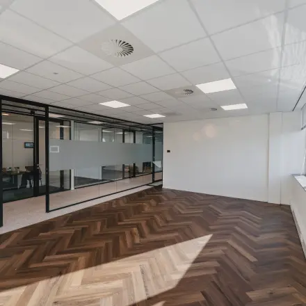 Spacious, unfurnished office to rent at Bos en Lommerplein 280 in Amsterdam West with large windows and wooden flooring.