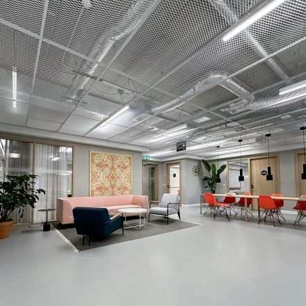Modern office space at Haarlemmerweg 331, Amsterdam West, featuring a chic seating area and vibrant red chairs ideal for rental.