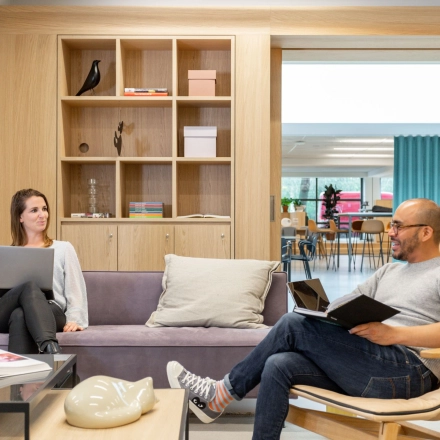 Bright office space at Haarlemmerweg 331 in Amsterdam West featuring a lounge area with people working on laptops and reading. Ideal for office space rental.