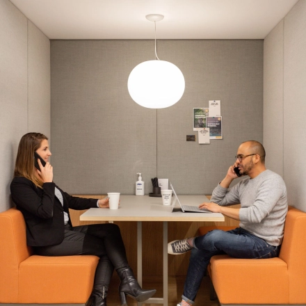 Two professionals engage in discussions within a compact workspace at Haarlemmerweg 331, Amsterdam West, ideal for office space rental.