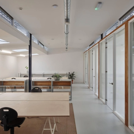 Spacious and modern office interior at Hondiusstraat 7H, Amsterdam West, featuring open workspaces with desks, chairs, and natural light, ideal for office space rental. Bright, clean design with plants adding a touch of greenery.
