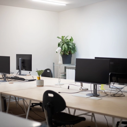 Modern workspace at Hondiusstraat 7H in Amsterdam West, featuring a clean, bright office setup with multiple computer monitors and plants on desks, ideal for office space rental.