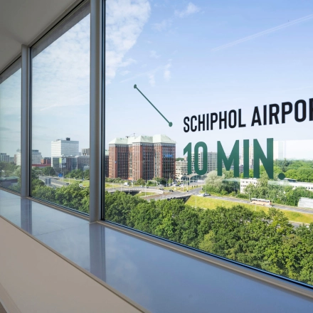 Large windows overlooking green space and nearby buildings at an office to rent in Amsterdam West.