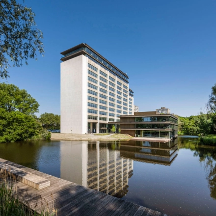 Exterior view of an office building at Nachtwachtlaan 20, Amsterdam West, ideal for office space rental, with a pond and surrounding greenery.