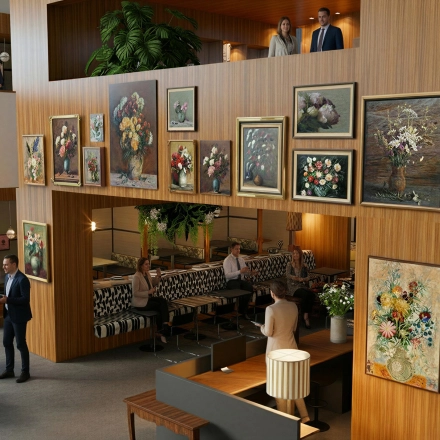 Modern office space with art-adorned wooden walls and people in business discussions, ideal for office space rental in Amsterdam Zuidas.