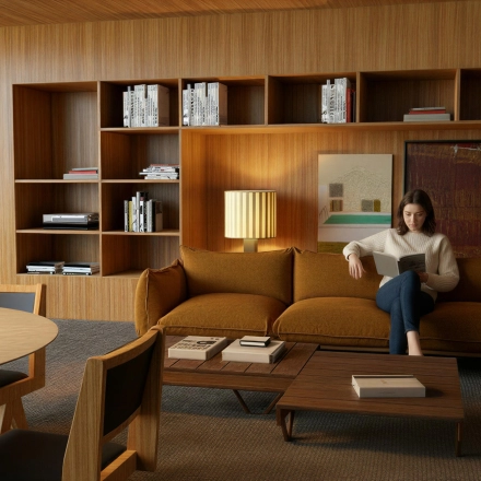 Comfortable office lounge in Amsterdam Zuidas with stylish wooden furniture and person reading, ideal for office space rental.