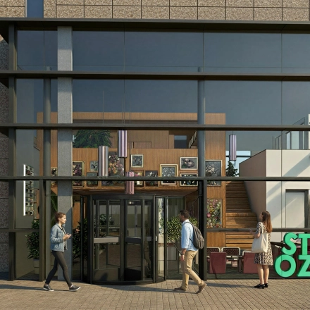 Exterior view of an office to rent at Barbara Strozzilaan 101 101, Amsterdam Zuidas, featuring glass facade and main entrance where people are entering the building.