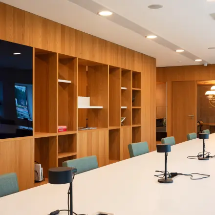Modern workspace featuring a long table with task lamps and seating in Amsterdam Zuidas, ideal for office space rental.