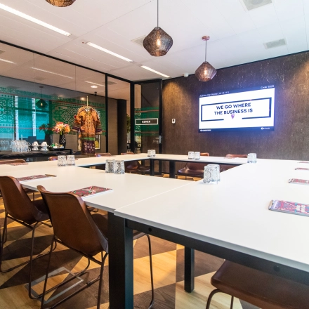 Modern conference room at Claude Debussylaan 7-29, Amsterdam Zuidas, featuring stylish decor, long tables, and a wall-mounted screen. Ideal for office space rental.