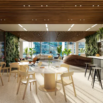 Modern office space in Amsterdam Zuidas with a stylish lounge area, featuring marble tables, wooden chairs, and indoor plants ideal for office space rental.