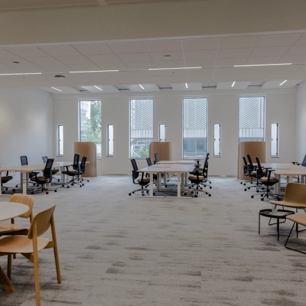 Spacious furnished office space rental at Fred. Roeskestraat 100, Amsterdam Zuidas, featuring multiple desks and chairs with large windows providing natural light. Ideal office to rent for collaborative work.