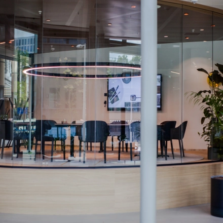 Modern conference room with a circular table and sleek chairs, set in a glass enclosure at Fred. Roeskestraat 100, ideal for office space rental in Amsterdam Zuidas.