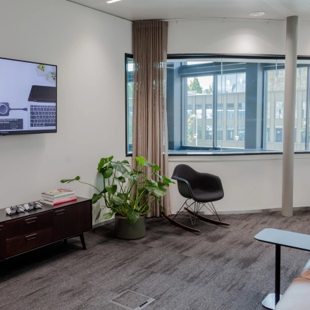 Furnished office space at Fred. Roeskestraat 100 in Amsterdam Zuidas with cozy seating and a flat-screen TV, ideal for office space rental.