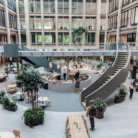 Spacious interior at Fred. Roeskestraat 100, Amsterdam Zuidas, showcasing an open floorplan with modern furnishings and individuals engaging in discussions and activities. Ideal for office space rental.