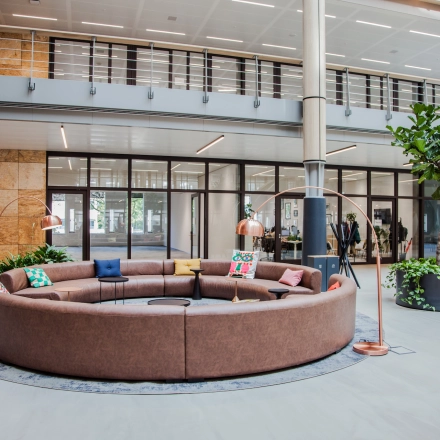 Spacious office lounge area with circular seating and plants at Fred. Roeskestraat 100, ideal for office space rental in Amsterdam Zuidas.