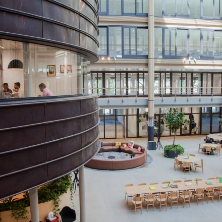 Spacious office at Fred. Roeskestraat 100, Amsterdam Zuidas, with people engaged in a meeting, showcasing modern office space rental options.