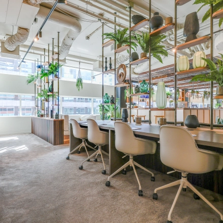 Bright and welcoming office space for rent at Gustav Mahlerlaan 308, Amsterdam Zuidas, featuring modern furnishings and open workstations with natural light and green accents.