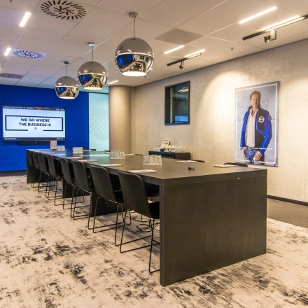 Modern conference room with a long table and sleek chairs, featuring a digital screen for presentations at Gustav Mahlerplein, ready for office space rental in Amsterdam Zuidas.