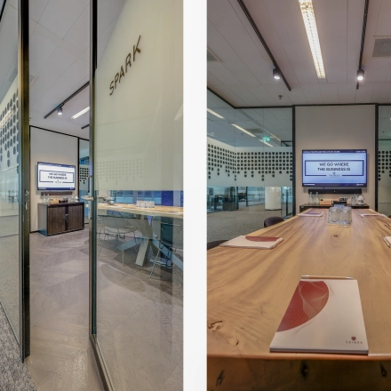 Modern office space at Gustav Mahlerplein 28 & 58-60, Amsterdam Zuidas, featuring a glass-walled meeting room with a large wooden table and audio-visual equipment, ideal for office space rental.