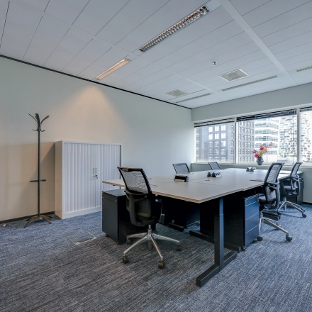 Bright office space with a large window offering city views, featuring a conference table and office chairs, perfect for meetings. Suitable for office space rental in Amsterdam Zuidas.