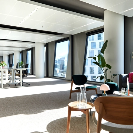 Bright office space for rent in Amsterdam Zuidas with large windows, modern furniture, and plants, perfect for an inspiring work environment.