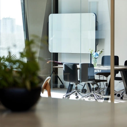Modern office space in Amsterdam Zuidas with a bright meeting area, featuring sleek chairs, a glass table, and green plants, ideal for office space rental.
