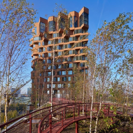 Exterior view of an office building at Hildegard Von Bingenstraat 44, Amsterdam Zuidas. Office space rental available with a unique architectural design surrounded by trees and walkways.