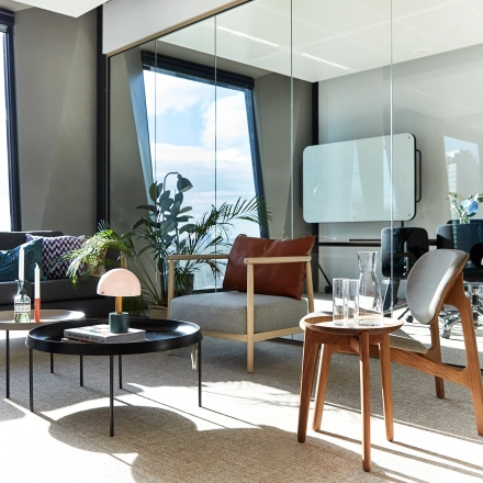 Modern office space for rent in Amsterdam Zuidas with stylish furniture, glass walls, and natural light through large windows. Ideal for office space rental with comfortable seating and plants.